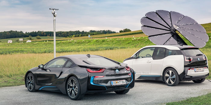 Two Electric BMWs Sit at a Charging Station Powered by a SmartFlower Solar Panel