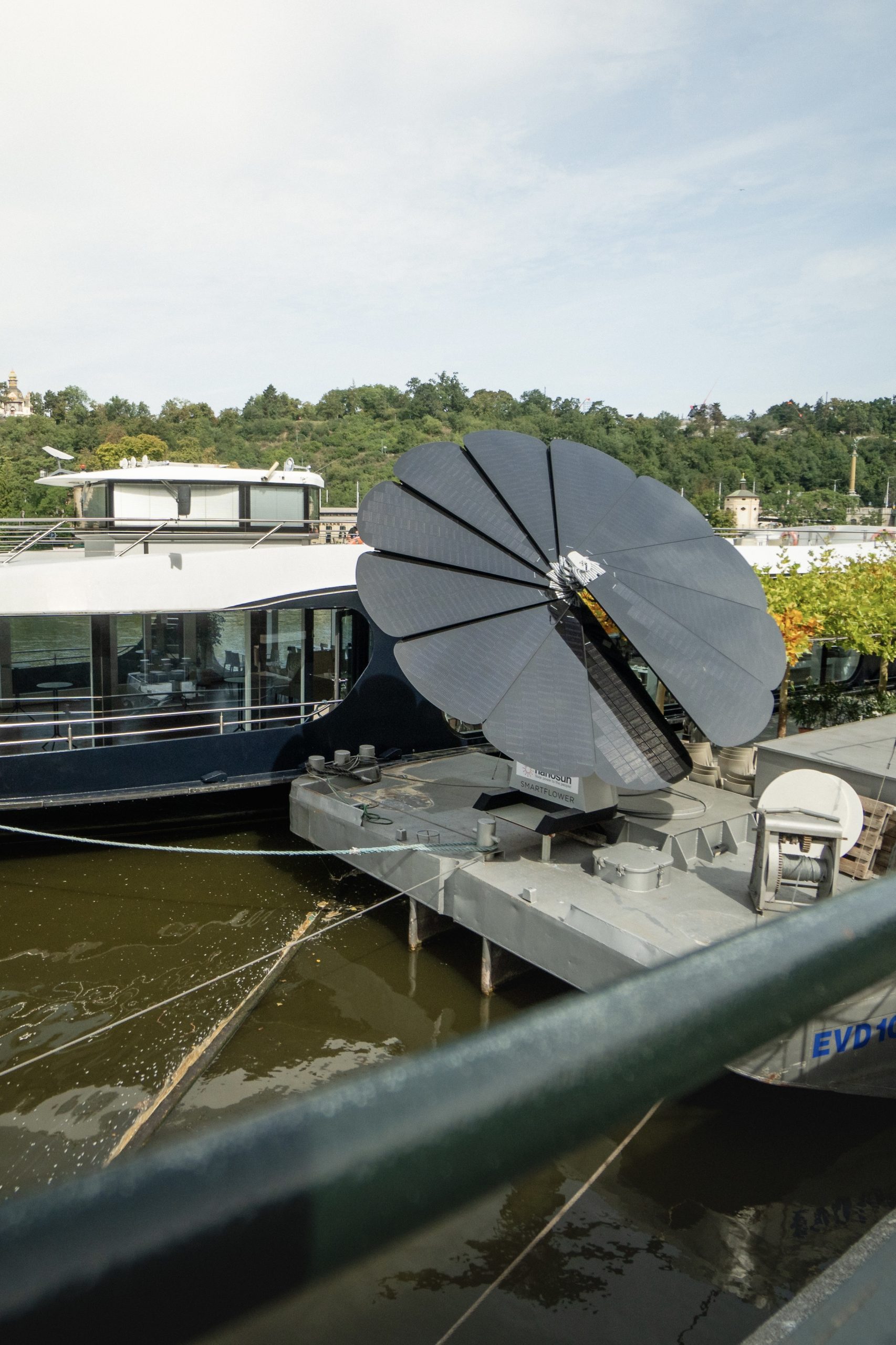 SmartFlower providing renewable energy at riverside marina with scenic background