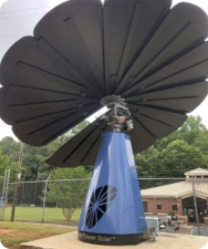 SmartFlower solar panel with blue base installed near school building and fenced outdoor area