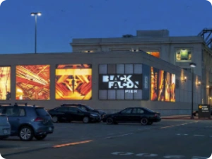 Night view of Black Falcon Pier showcasing glowing art panels and signage in waterfront district