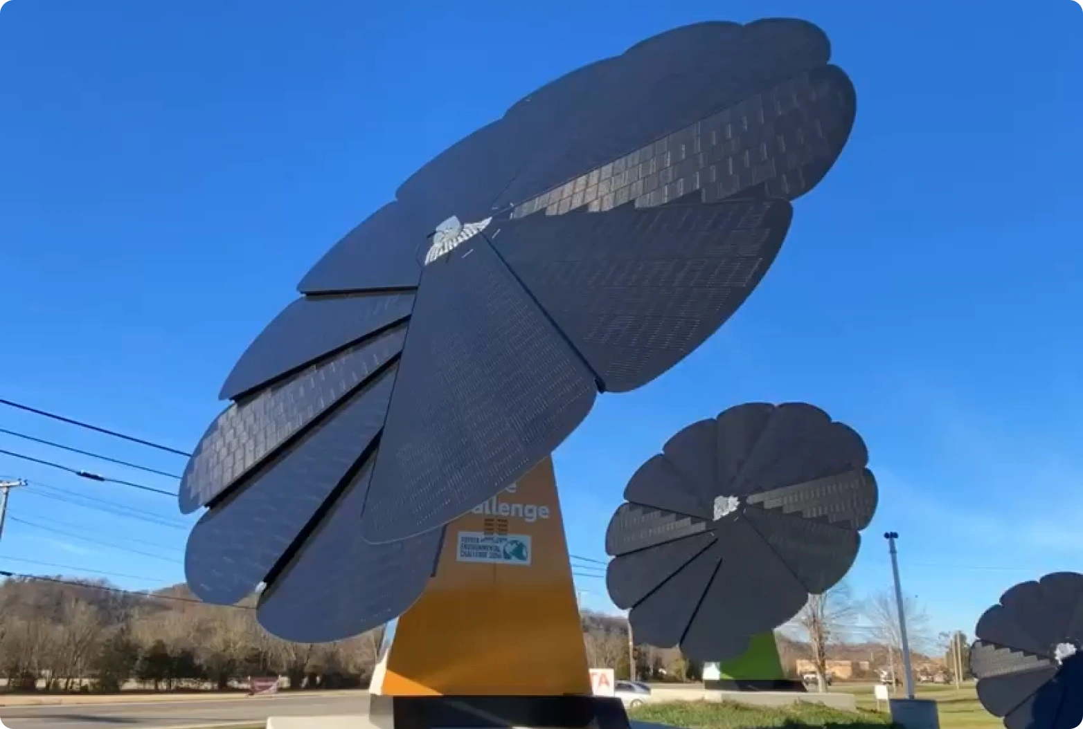 Three SmartFlower solar units prominently displayed against a vibrant blue sky