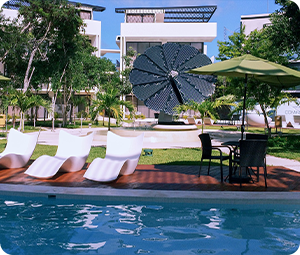 SmartFlower in background center with a pool in front with some lounge chairs and an umbrella at Los Amigos hotel.